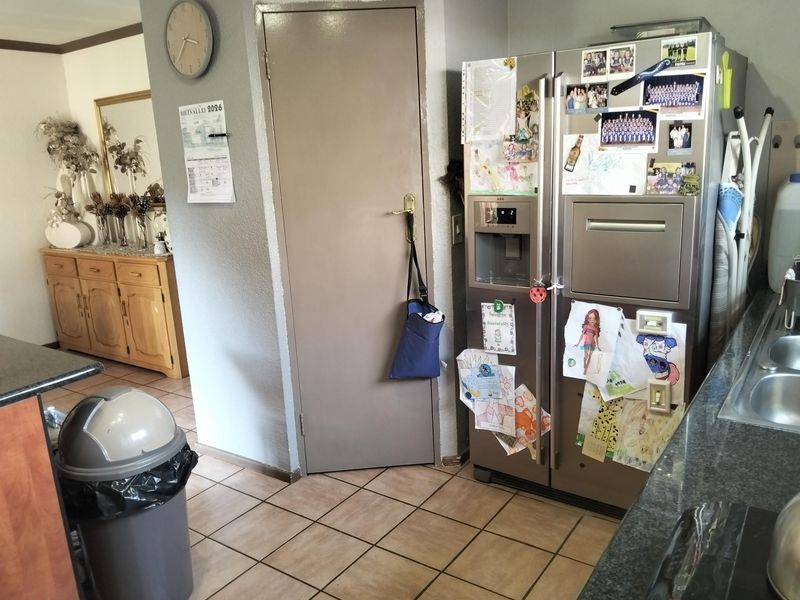 A functional kitchen area featuring tiled flooring, granite countertops, and a built-in stainless steel refrigerator, providing a practical workspace.