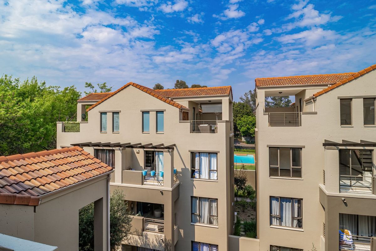 Exterior view of a multi-story apartment complex featuring terracotta tiled roofs, private balconies, and modern aluminium window frames.
