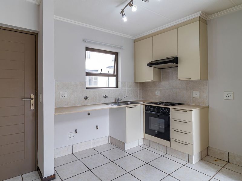 A functional kitchen featuring built-in cabinetry, a gas hob with extractor, and tiled finishes. The space is clean and ready for personalization.