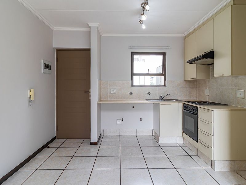 A functional kitchen featuring tiled flooring, built-in cabinetry, a hob, oven, extractor fan, and a tiled backsplash.