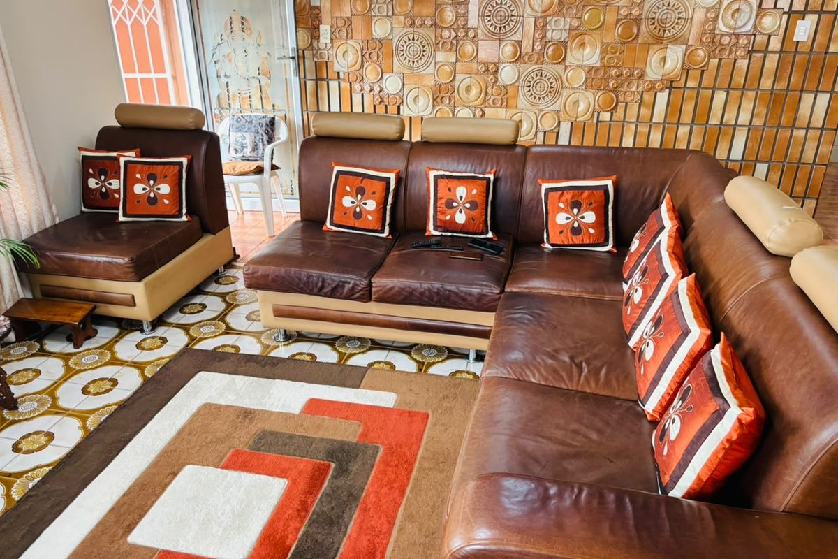 A living room featuring distinctive patterned ceramic floor tiles and a decorative textured feature wall with a sliding glass door leading outside.