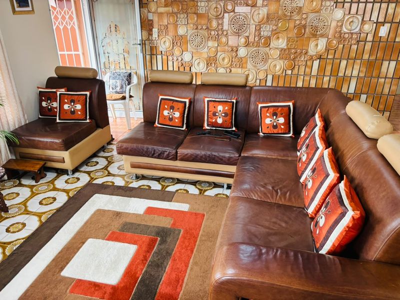 A living room featuring distinctive patterned ceramic floor tiles and a decorative textured feature wall with a sliding glass door leading outside.