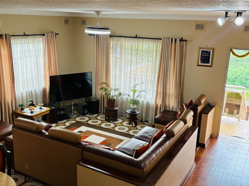 A spacious living room featuring tiled flooring, ceiling fan, and track lighting, with direct access to an outdoor balcony area.