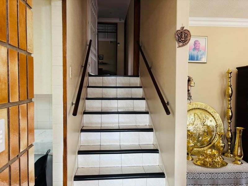 A central staircase featuring tiled steps with contrasting black nosing and wooden handrails, providing access to the upper level of the home.
