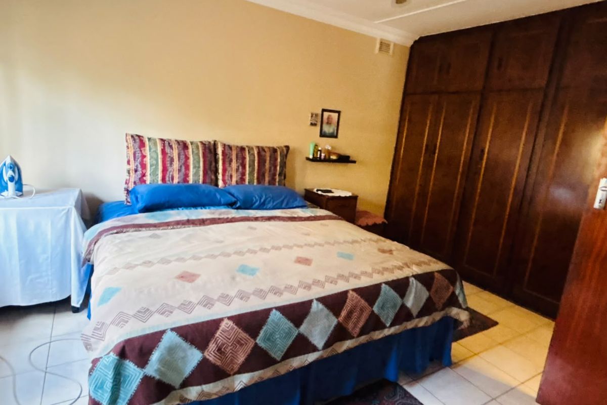 A bedroom featuring built-in wooden cupboards, tiled flooring, and a ceiling fan.
