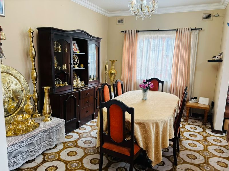 A formal dining room featuring decorative patterned ceramic floor tiles, a classic chandelier, and traditional crown molding.
