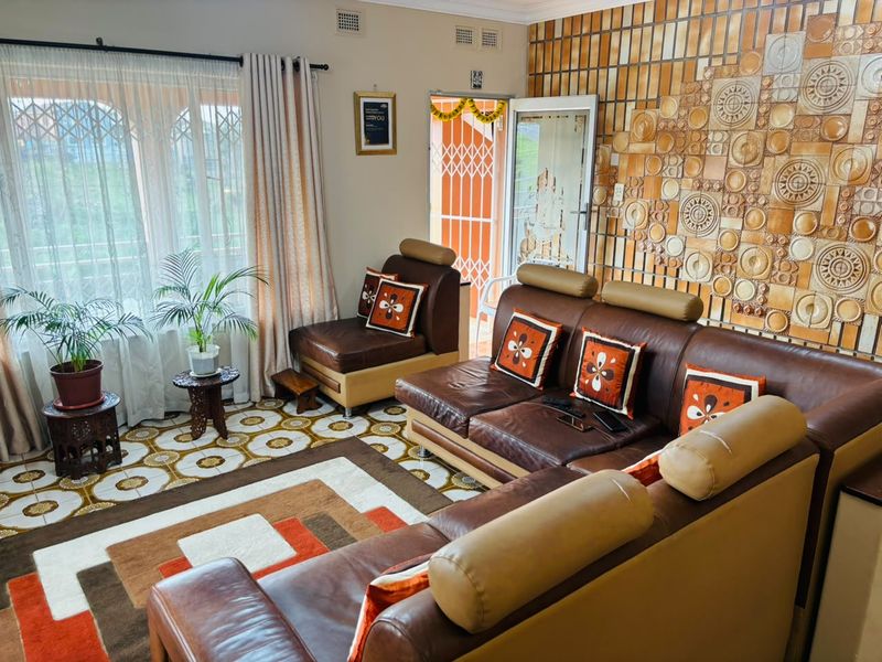 A living room featuring a distinctive textured ceramic feature wall, patterned floor tiles, and access to an outdoor area through a security gate.