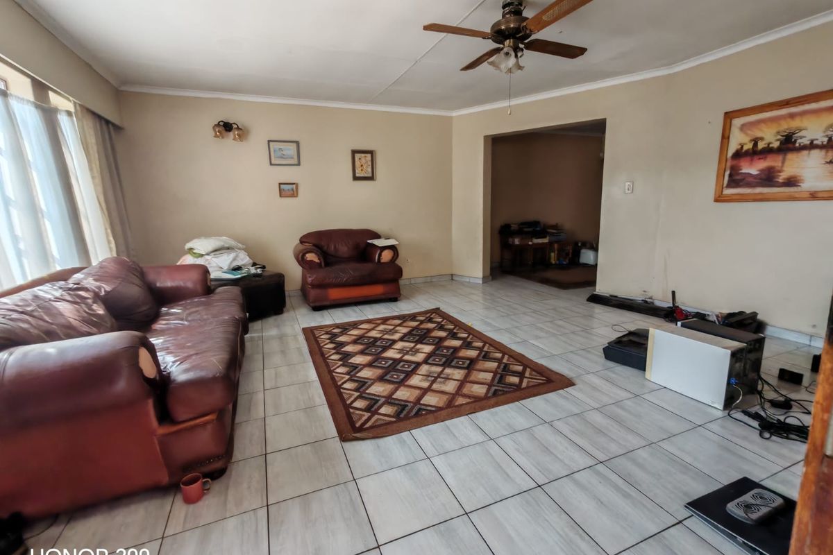 Spacious living room featuring tiled flooring and a ceiling fan, offering a versatile layout with potential for modernization.