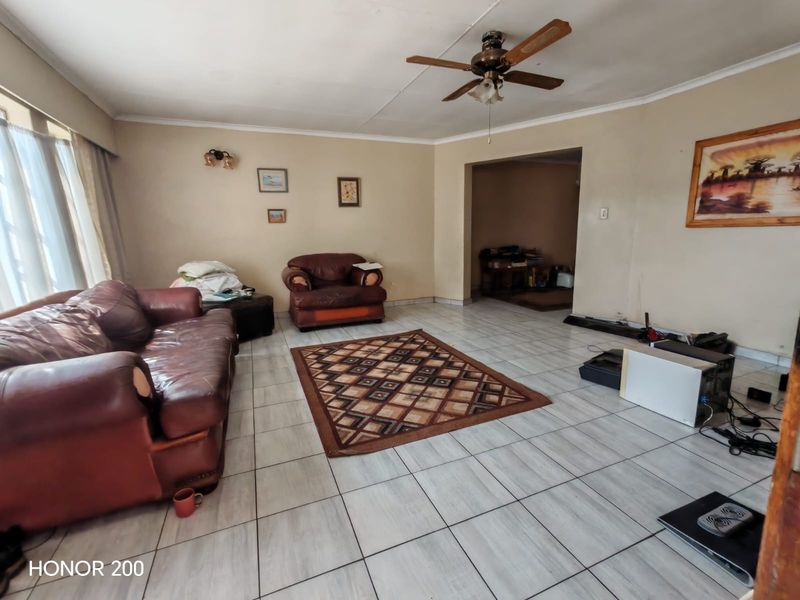Spacious living room featuring tiled flooring and a ceiling fan, offering a versatile layout with potential for modernization.