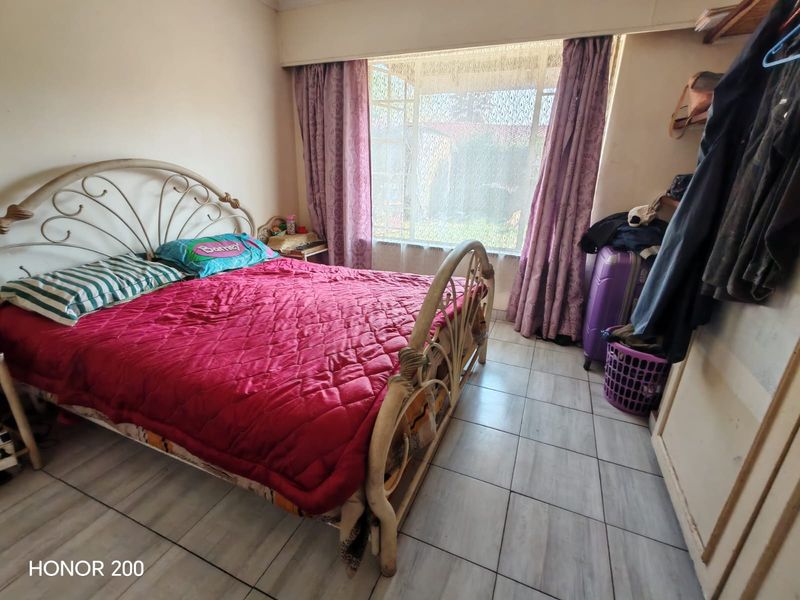 A bedroom featuring tiled flooring and a built-in cupboard, offering a functional space with potential for cosmetic updates to enhance its appeal.