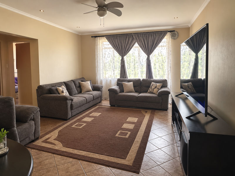 A well-maintained living room featuring tiled flooring, recessed ceiling lighting, and a central ceiling fan, offering a comfortable and functional living space.