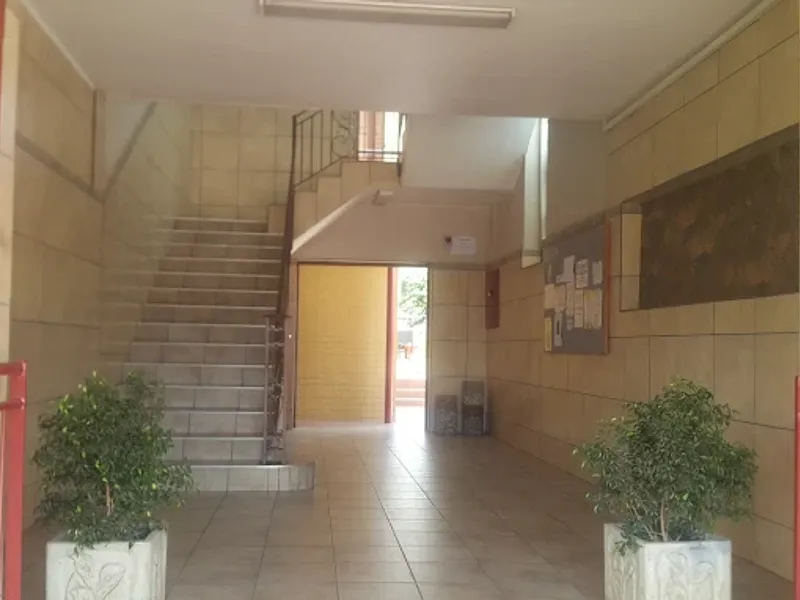 A communal apartment building entrance lobby featuring tiled flooring, a staircase, and an intercom system.