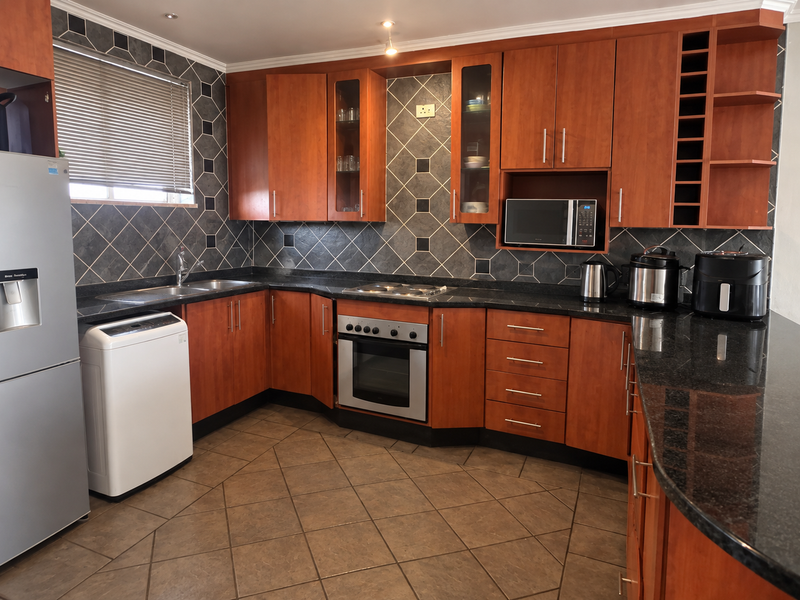 A functional kitchen featuring warm-toned wooden cabinetry, granite countertops, a built-in oven, and a tiled backsplash with a dedicated wine storage rack.