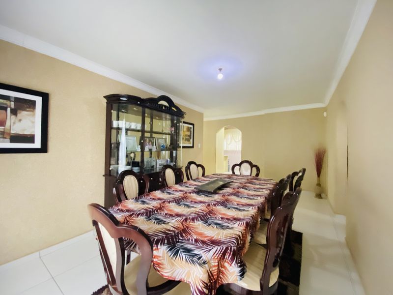 A dining room featuring tiled flooring, coved ceiling details, and an arched entryway leading to adjacent living spaces.