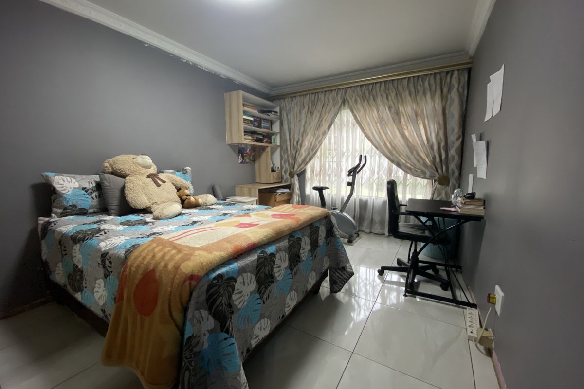 A bedroom featuring tiled flooring, built-in shelving, and decorative cornicing, offering a functional space with potential for cosmetic updates.