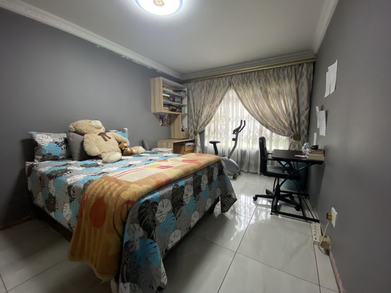 A bedroom featuring tiled flooring, built-in shelving, and decorative cornicing, offering a functional space with potential for cosmetic updates.