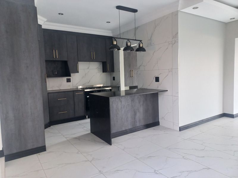 Modern kitchen featuring dark matte cabinetry, a central island, marble-look wall and floor tiles, and integrated gas cooking appliances.