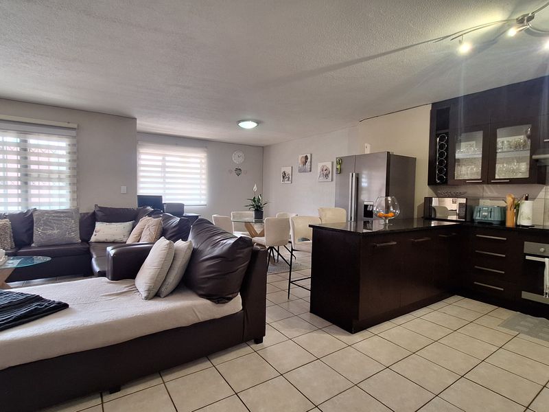 Spacious open-plan living area featuring a modern kitchen with dark cabinetry, granite countertops, built-in oven, and tiled flooring throughout.