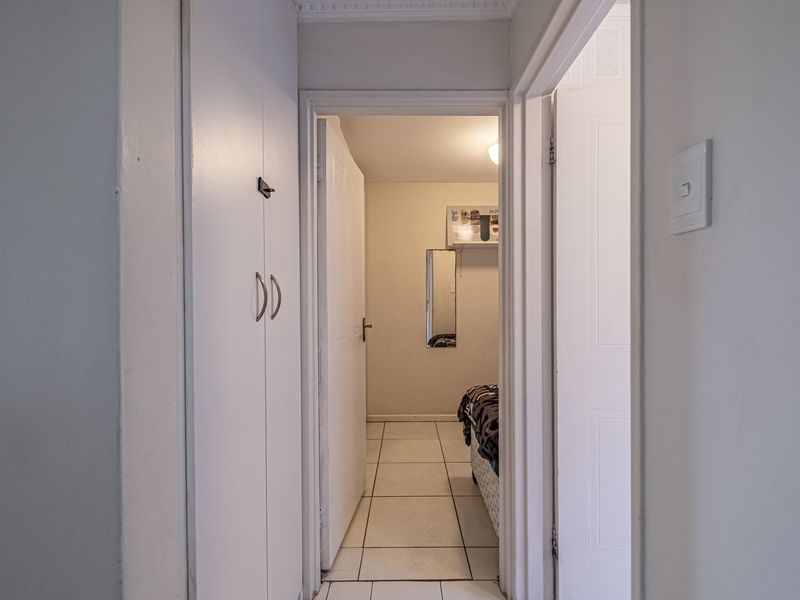 A functional hallway featuring tiled flooring and built-in storage cupboards, providing access to adjacent rooms within the apartment.