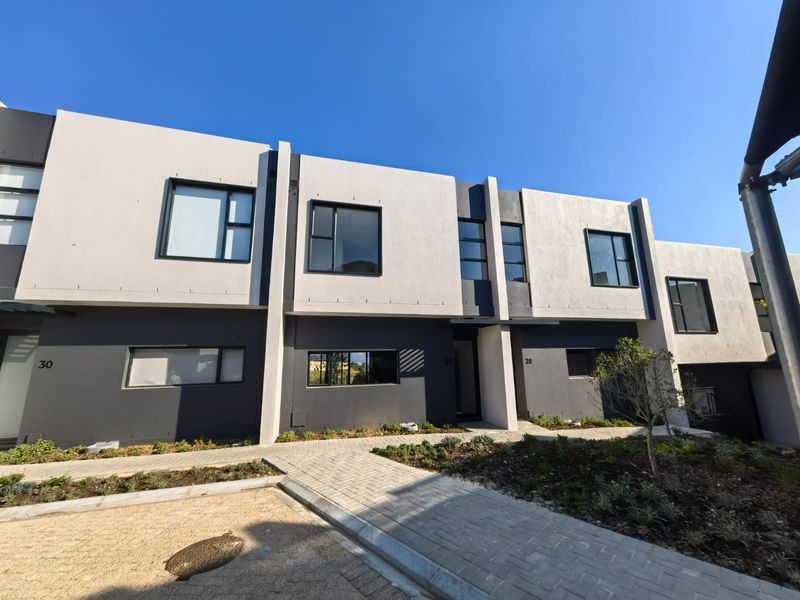 Modern multi-unit residential facade featuring contemporary architectural design, clean lines, and paved pedestrian access paths.