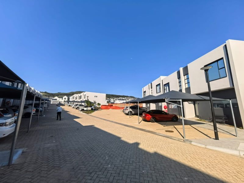 A modern residential complex featuring paved driveways and covered carport parking bays for residents.