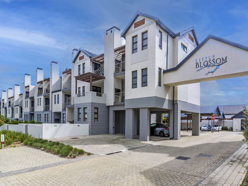 Modern apartment complex exterior featuring a paved driveway, covered parking bays, and contemporary architectural design with balconies.
