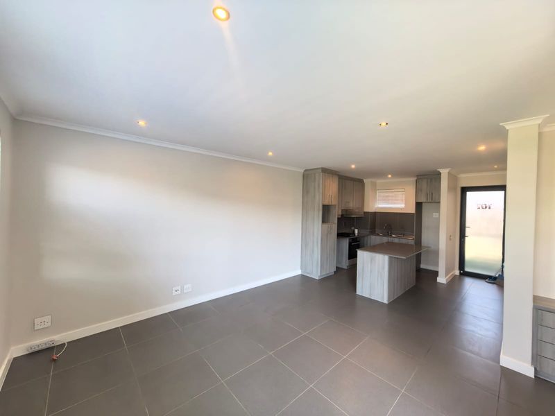 Modern open-plan living area featuring tiled floors, recessed lighting, and a contemporary kitchen with built-in cabinetry and a central island.