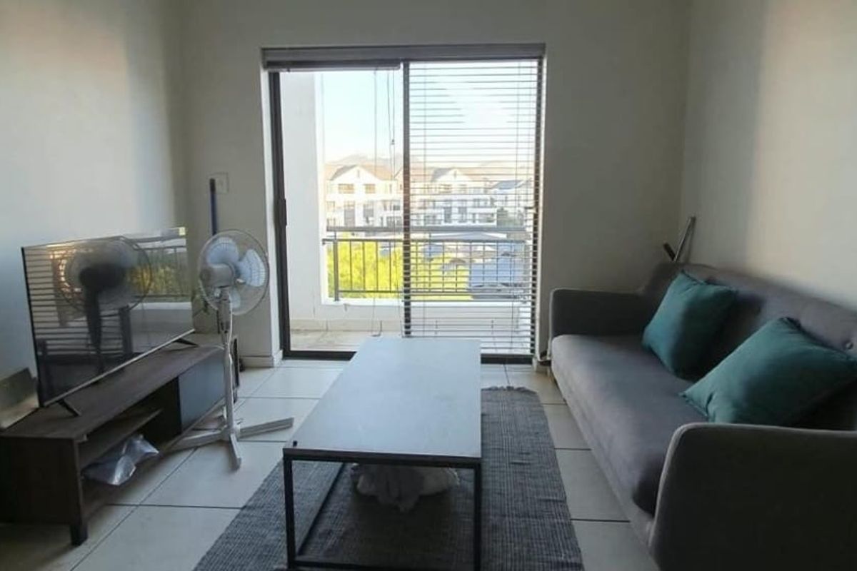 A living room featuring tiled flooring and a sliding glass door that provides access to a balcony with neighbourhood views.