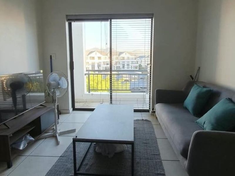 A living room featuring tiled flooring and a sliding glass door that provides access to a balcony with neighbourhood views.