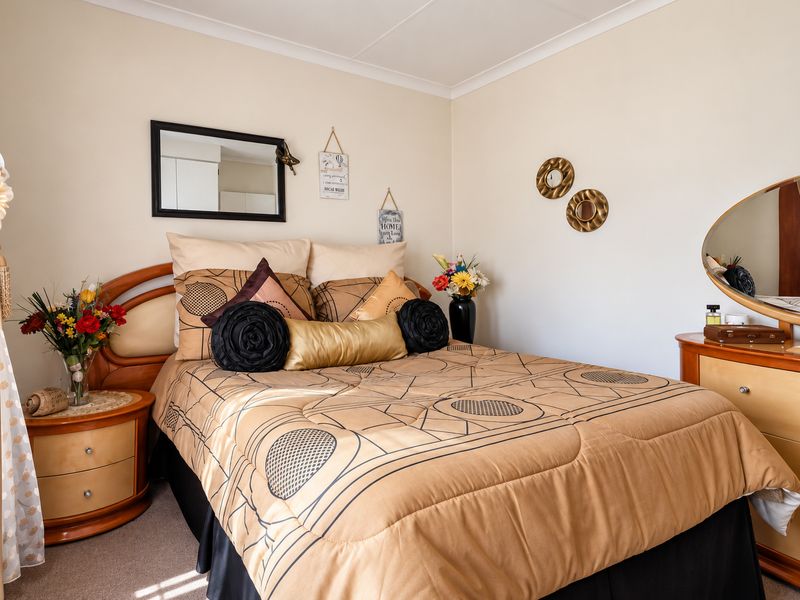 A well-maintained bedroom featuring neutral wall tones, carpeted flooring, and classic cove cornice detailing.
