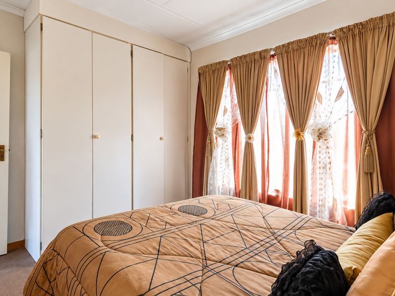 A bedroom featuring built-in cupboards and carpeted flooring, offering a functional space with natural light through the window.