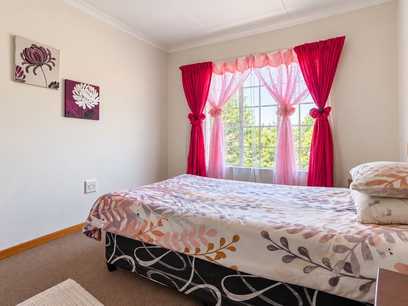 A well-lit bedroom featuring carpeted flooring, a window with security bars, and neutral wall finishes.