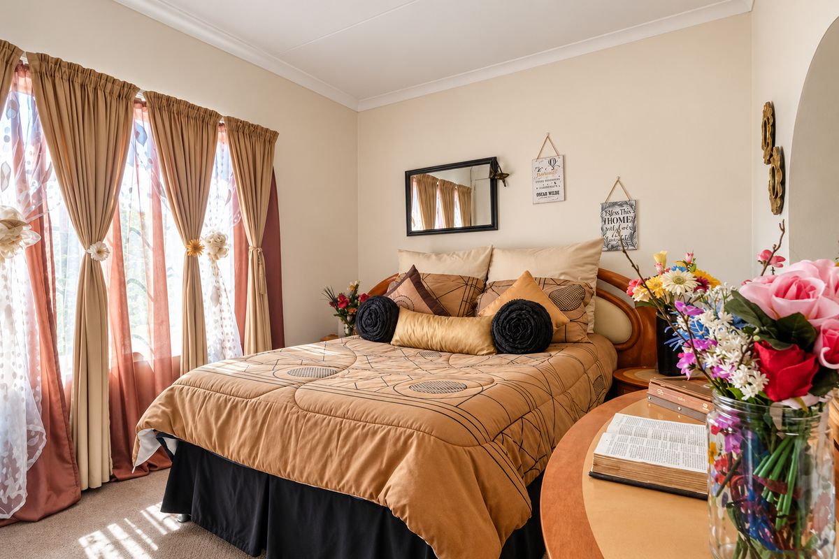 A well-lit bedroom featuring neutral wall tones, coving, and carpeted flooring, providing a comfortable and functional living space.