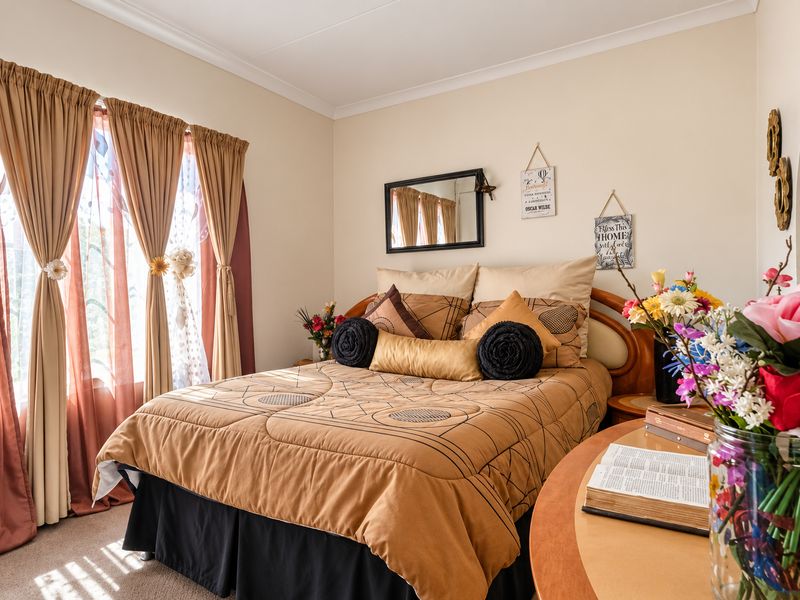 A well-lit bedroom featuring neutral wall tones, coving, and carpeted flooring, providing a comfortable and functional living space.
