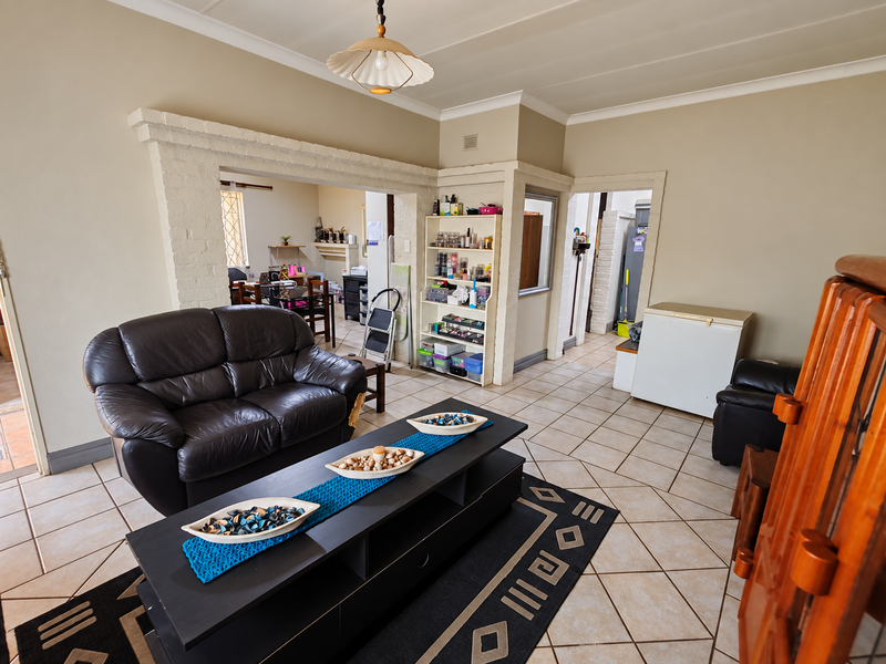Open plan living area featuring tiled flooring, an exposed brick archway, and coved ceilings, providing a functional layout with access to adjacent rooms.