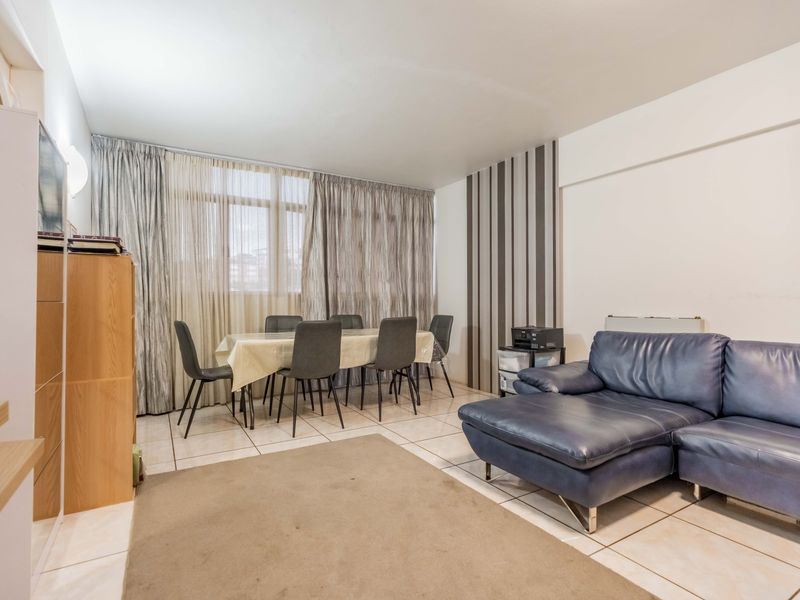 Open-plan living and dining area featuring tiled flooring, neutral wall finishes, and large windows allowing for natural light.