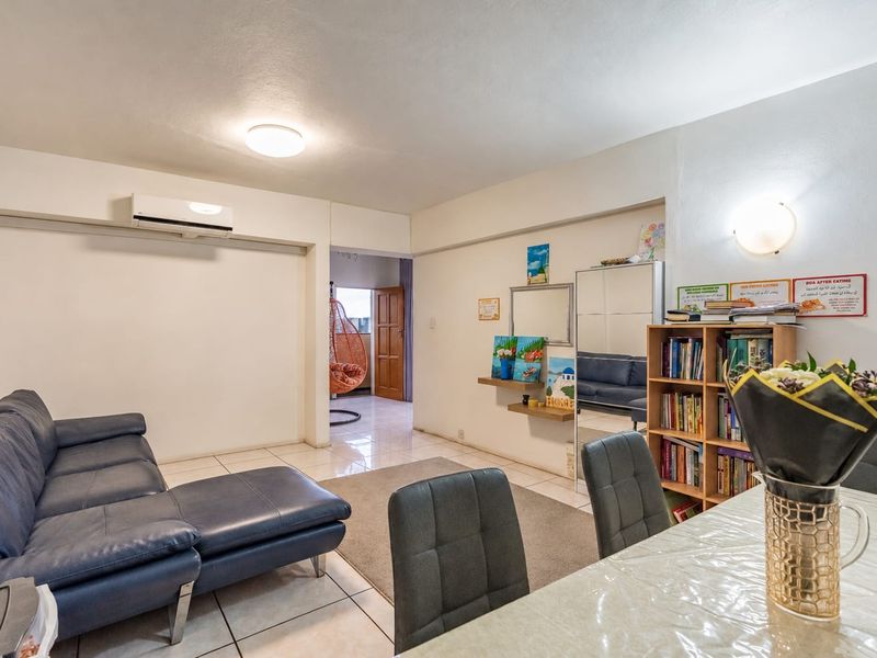 Open-plan living and dining area featuring tiled flooring, a wall-mounted air conditioning unit, and neutral wall finishes.