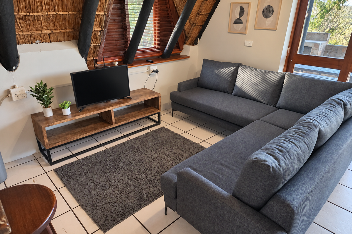 A cozy living room featuring a unique thatched roof with exposed timber rafters, tiled flooring, and direct access to an outdoor area.