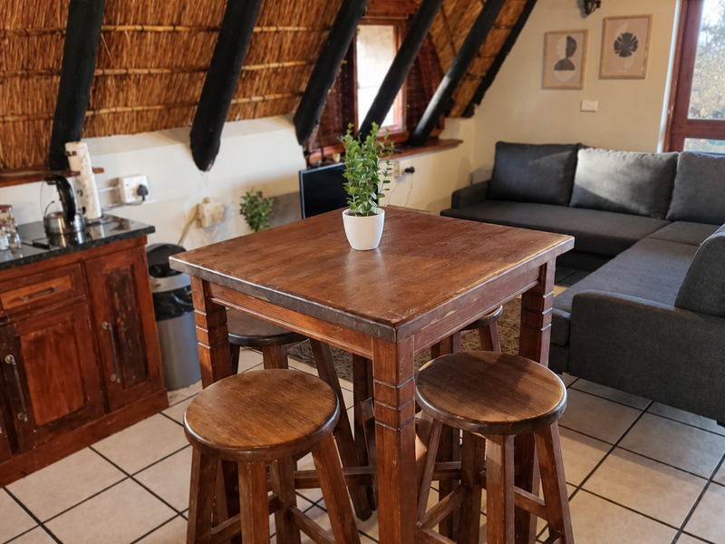 Open-plan living area featuring a distinctive thatched roof with exposed timber rafters and tiled flooring, creating a rustic and cozy atmosphere.