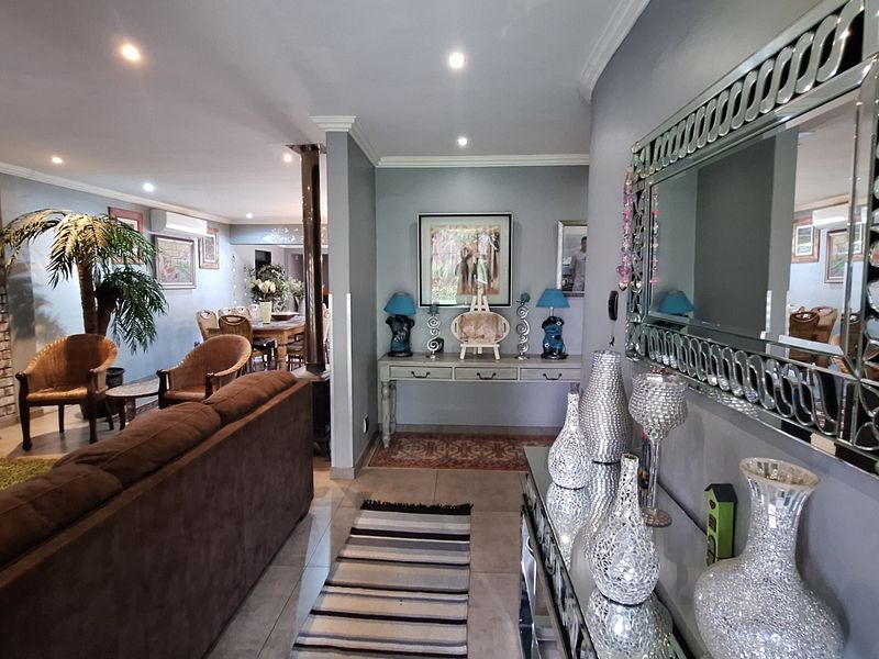 Spacious open-plan living area featuring tiled floors, recessed lighting, a striking exposed brick feature wall, and a modern freestanding fireplace.