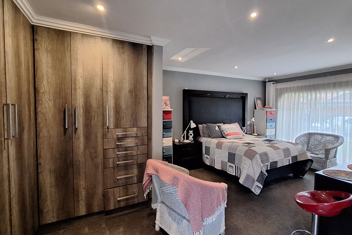 Spacious bedroom featuring extensive built-in wooden cabinetry, recessed downlighting, and large sliding glass doors providing natural light.
