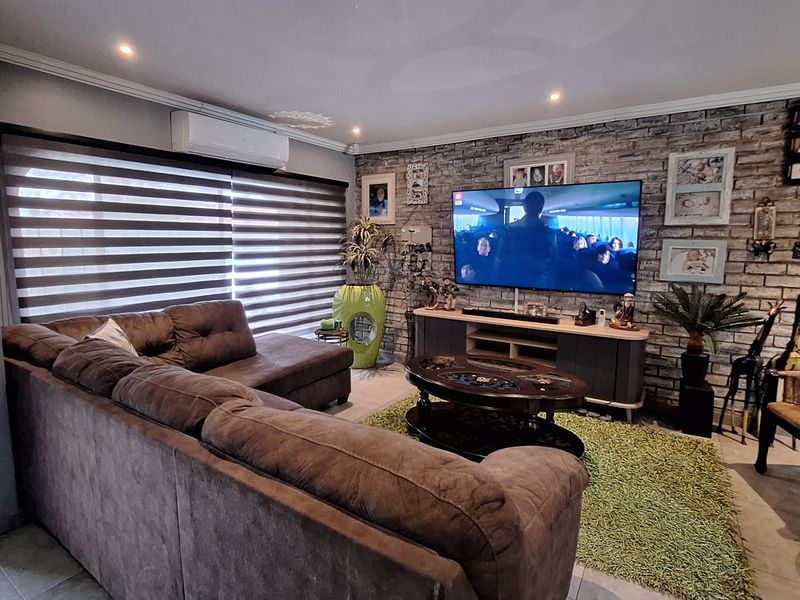 A comfortable living room featuring an exposed brick accent wall, recessed downlighting, and a wall-mounted air conditioning unit.