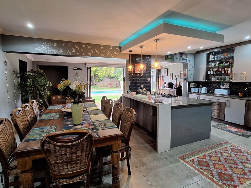 Spacious open-plan kitchen and dining area featuring a modern kitchen island, contemporary cabinetry, and seamless flow to the outdoor patio and pool area.