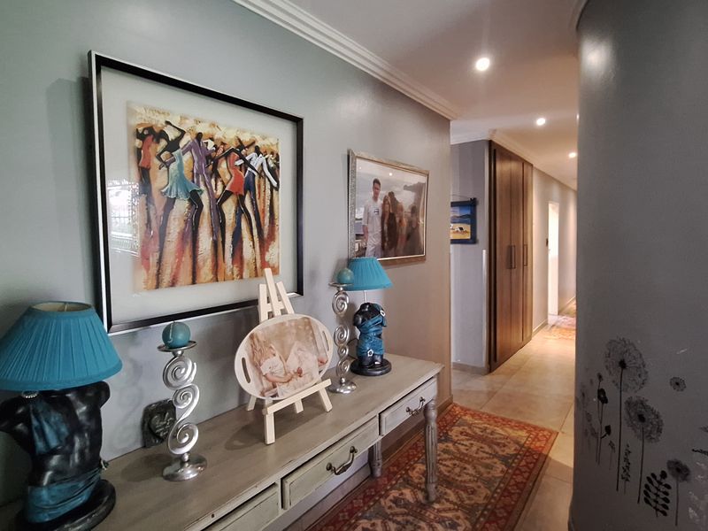 A well-maintained hallway featuring tiled flooring, recessed downlighting, and built-in cabinetry, leading towards the interior living spaces of the home.