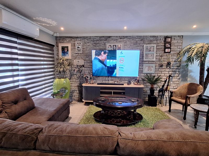 A comfortable living room featuring a textured faux brick accent wall, recessed downlighting, and a wall-mounted split-system air conditioning unit.