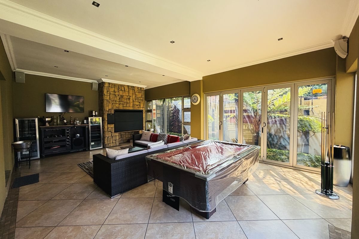 Spacious living area featuring stone-clad fireplace, tiled flooring, and large aluminium stacker doors providing seamless access to the garden.