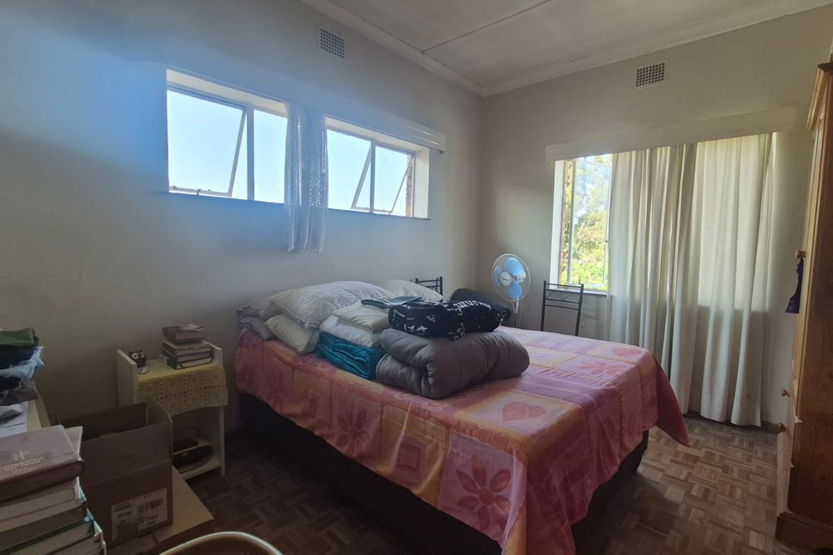 A bedroom featuring parquet flooring, cornicing, and natural light from multiple windows. The space requires cosmetic updates to improve its overall condition.