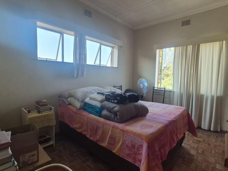 A bedroom featuring parquet flooring, cornicing, and natural light from multiple windows. The space requires cosmetic updates to improve its overall condition.