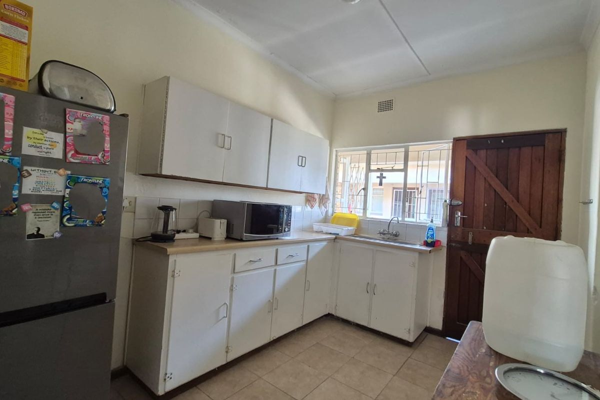 A functional kitchen featuring white built-in cabinetry, laminate countertops, and tiled flooring, offering a practical layout with potential for modern updates.
