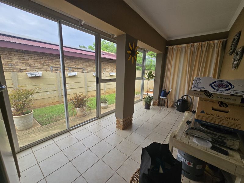 A covered patio area featuring tiled flooring and large sliding glass doors that provide direct access to the rear garden.